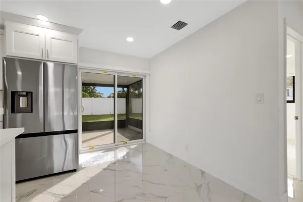 a view of a kitchen with refrigerator and an empty room