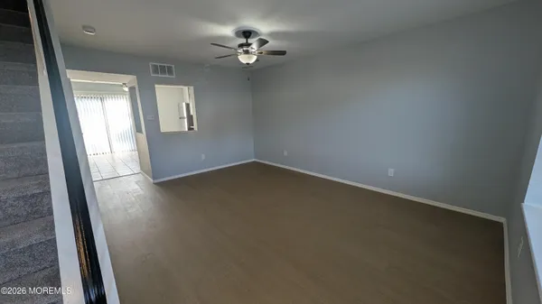 an empty room with wooden floor fan and windows
