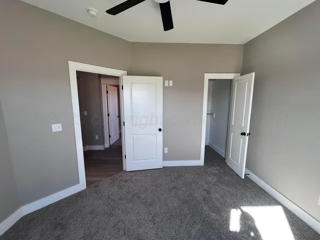 an empty room with ceiling fan and window