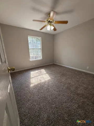 en empty room with windows and chandelier fan