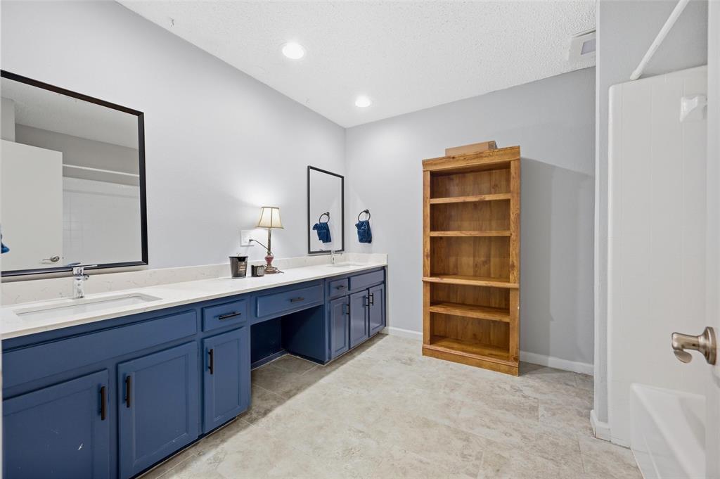 608 Ridgewood Circle Hurst, TX 76054 - Photo 27 of 38 Double vanity with blue cabinetry, white countertops, built-in storage, and two framed mirrors