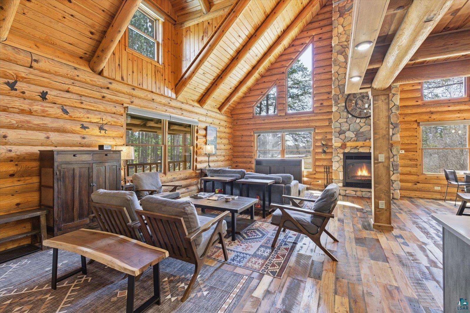 7185 Giants Ridge Road Embarrass, MN 55732 - Photo 9 of 47 Expansive great room featuring wood-finish flooring, vaulted ceilings with exposed beams, a stone-clad fireplace, and large windows