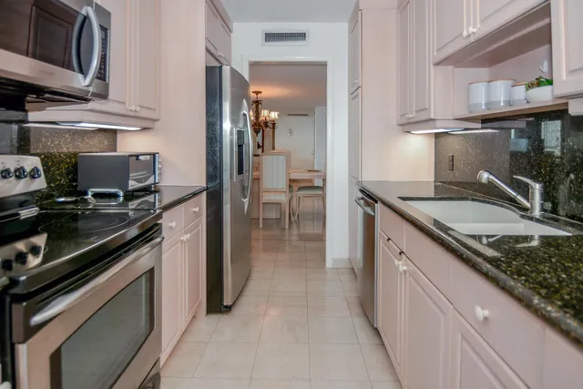 a kitchen with granite countertop stainless steel appliances a sink stove top oven and microwave