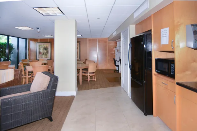 a living room with stainless steel appliances granite countertop furniture a refrigerator a fireplace a sink and a window