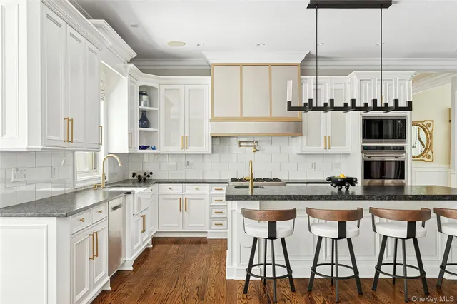 a kitchen with stainless steel appliances granite countertop a stove top oven a sink a dining table and chairs