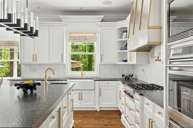 a kitchen with stainless steel appliances granite countertop a sink a stove and a wooden floors