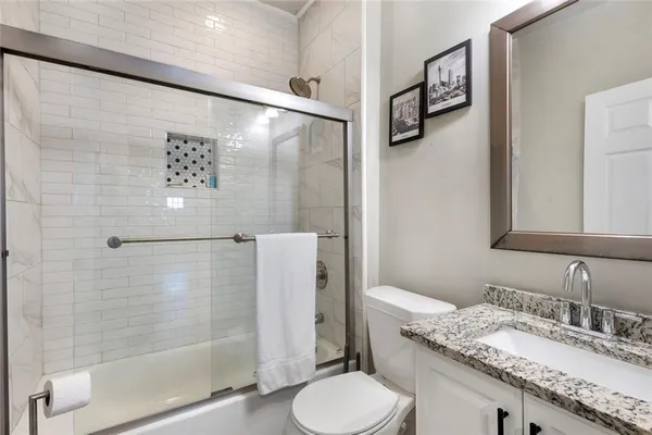a bathroom with a granite countertop sink toilet and shower