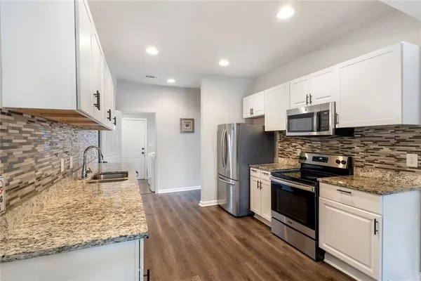 a kitchen with stainless steel appliances granite countertop a sink stove and refrigerator