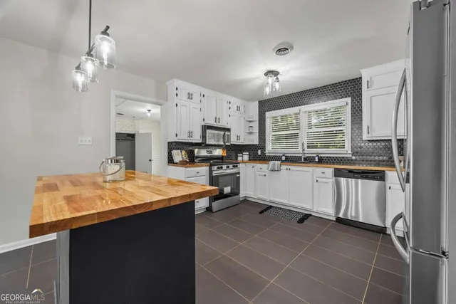 a kitchen with stainless steel appliances a sink a stove a refrigerator cabinets and a window