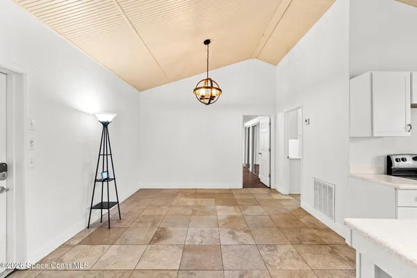 a view of a room with a chandelier fan and kitchen view