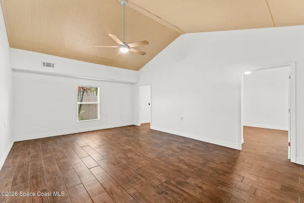 an empty room with wooden floor and windows