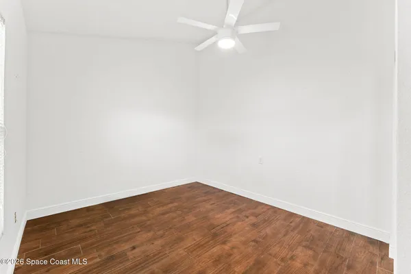 an empty room with wooden floor and fan
