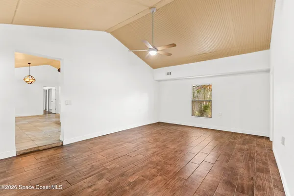 an empty room with wooden floor and fan