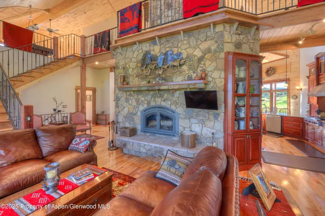 a living room with furniture a large window and wooden floor