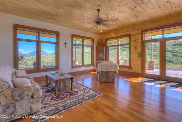a living room with furniture a table and large windows