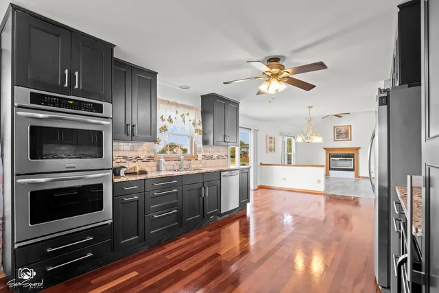 a kitchen with stainless steel appliances a stove a refrigerator and a view of living room