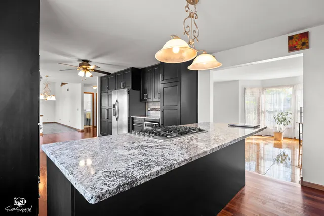 a kitchen with stainless steel appliances granite countertop a refrigerator a sink dishwasher a stove and white countertops with wooden floor