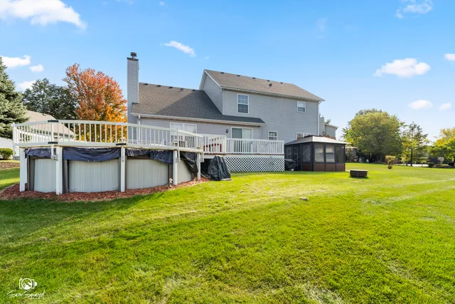 a view of a house with pool and chairs next to a yard