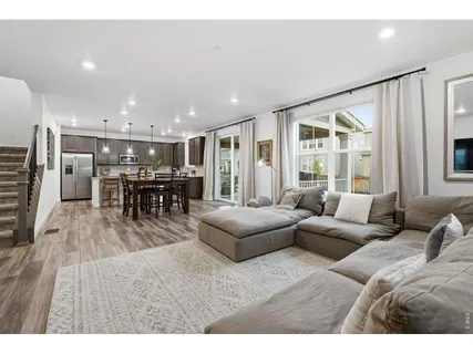 a kitchen with kitchen island granite countertop a dining table chairs and refrigerator