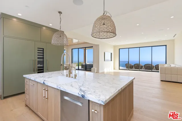 a view of a kitchen island a chandelier wooden cabinets and entryway