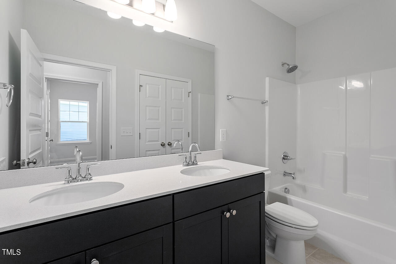 63 Beech Tree Way, Unit 139 Garner, NC 27529 - Photo 21 of 25 a bathroom with a double vanity sink toilet and a mirror