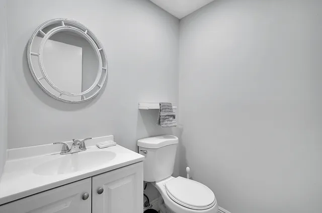 a bathroom with a granite countertop toilet a sink and mirror