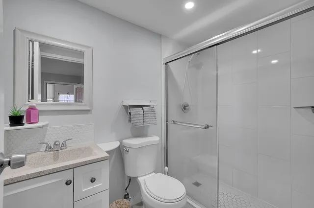 a bathroom with a granite countertop sink toilet a mirror and shower