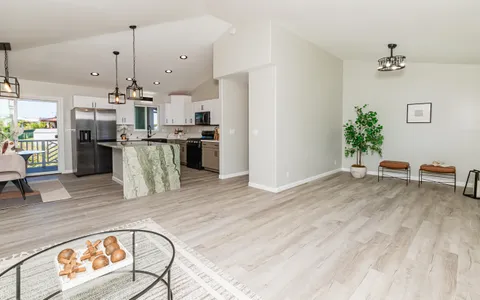 a kitchen with stainless steel appliances granite countertop a refrigerator a stove a sink dishwasher and white cabinets with wooden floor