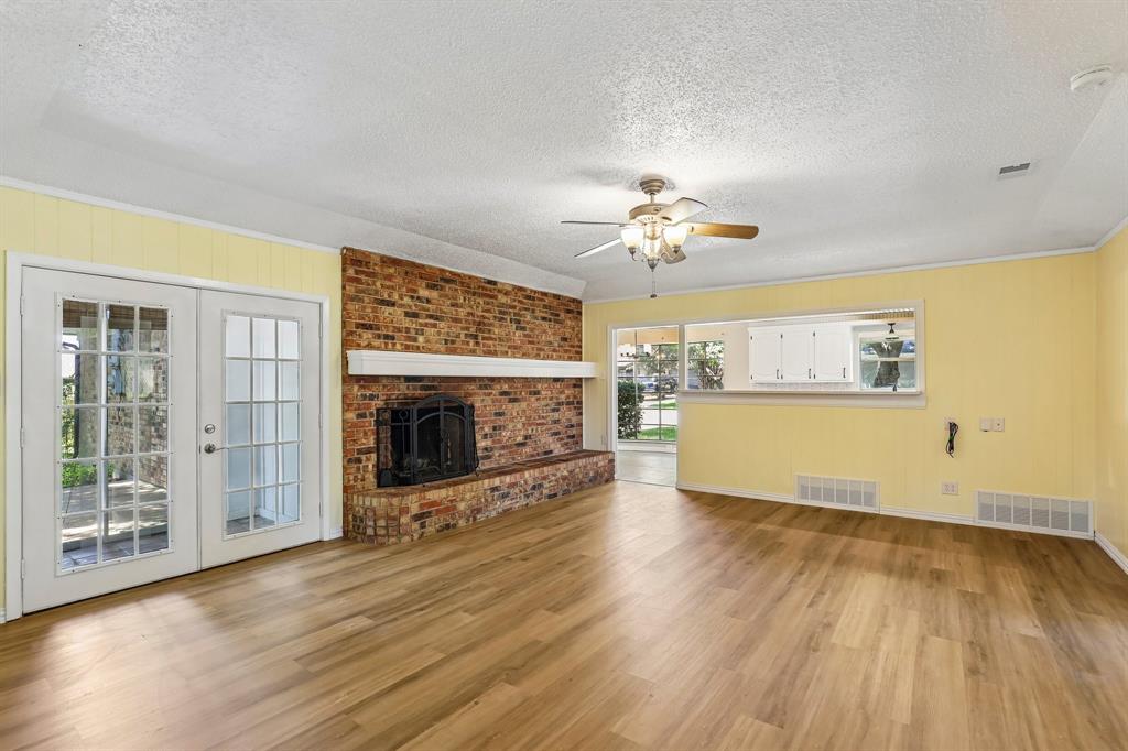 1600 South Timber Court Benbrook, TX 76126 - Photo 5 of 30 Spacious living area featuring wood-finish flooring, a brick-front fireplace, and double glass-paned doors