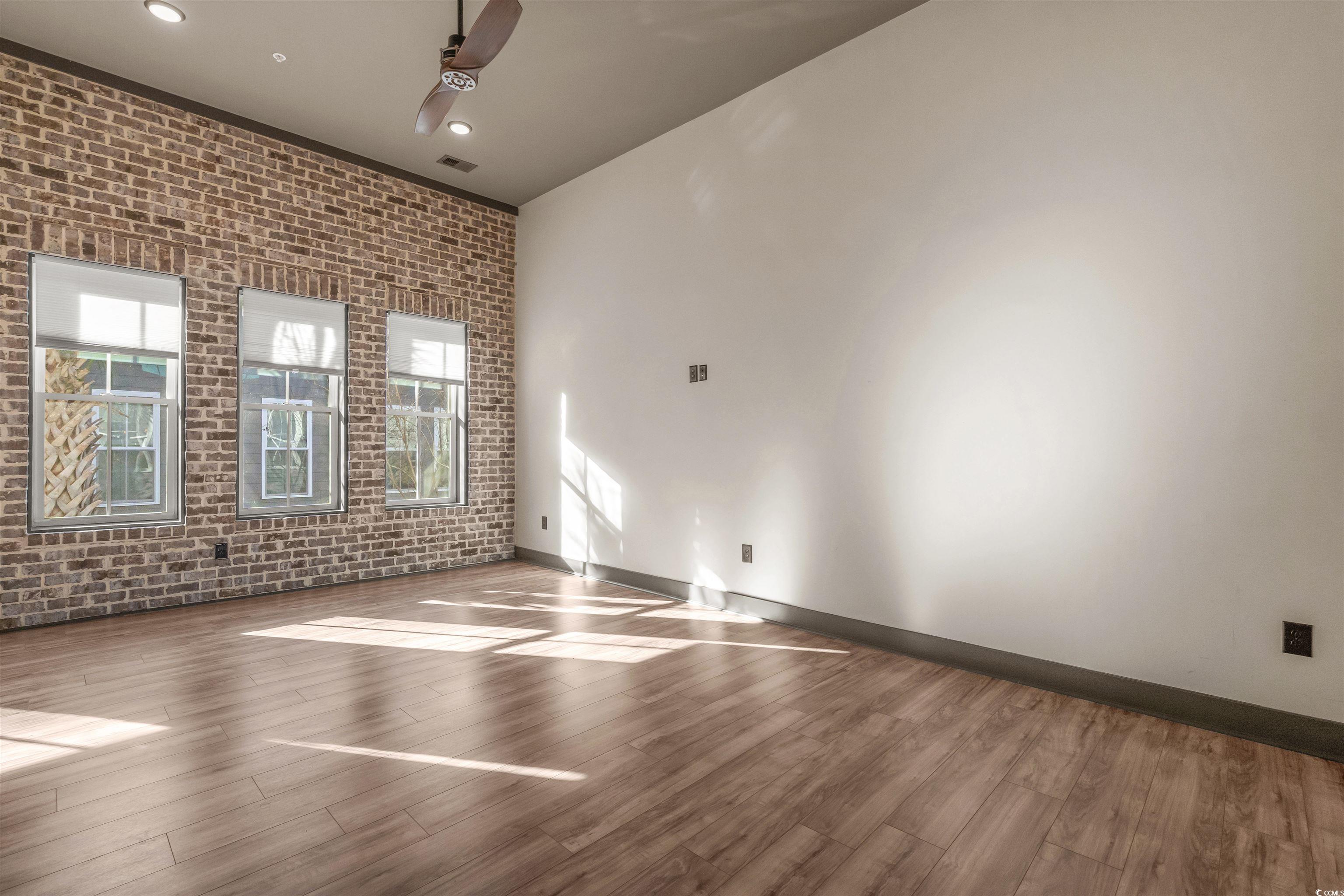 80 Shady Oak Lane Murrells Inlet, SC 29576 - Photo 5 of 31 Empty room featuring brick wall, wood finished floors, a ceiling fan, and recessed lighting