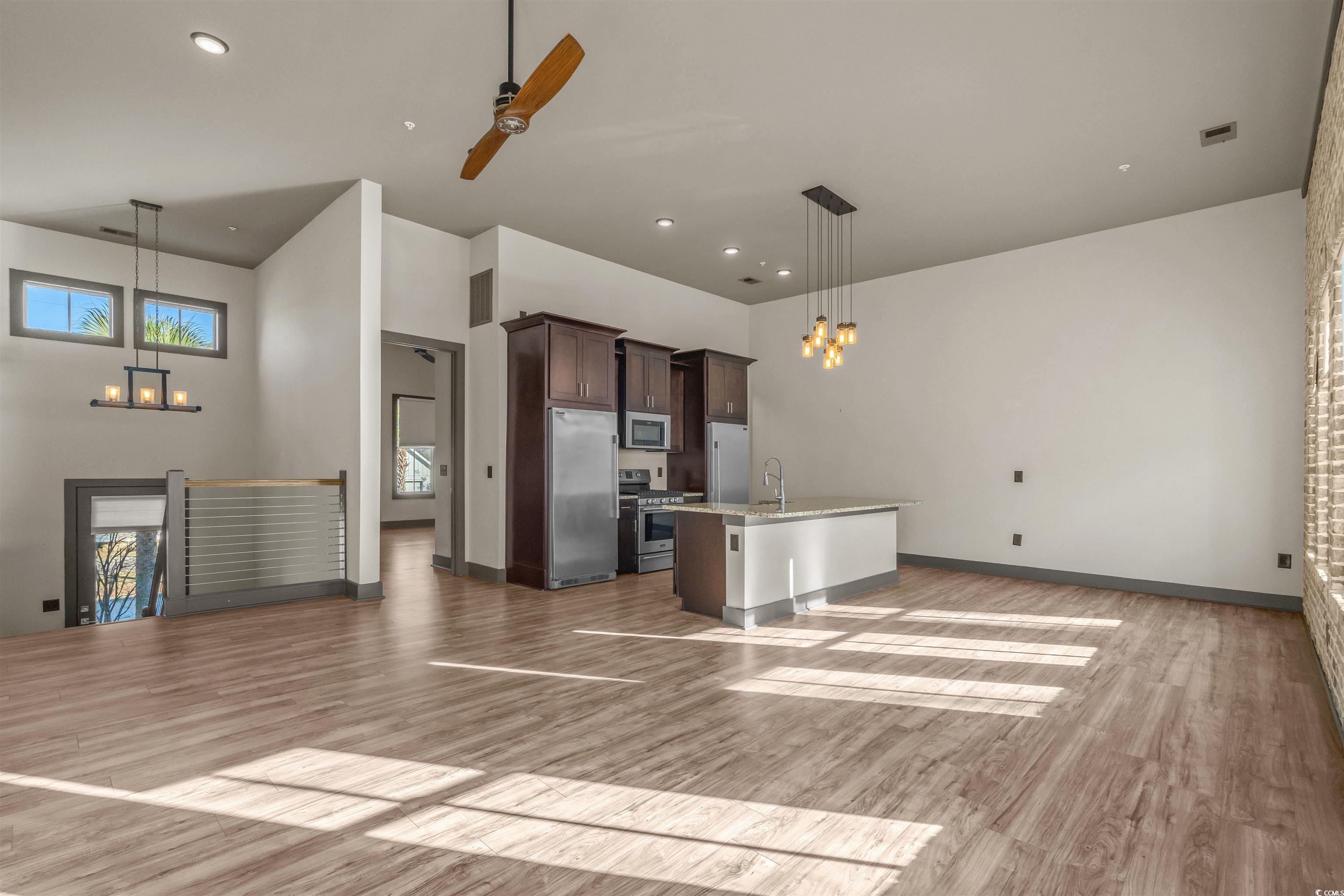 80 Shady Oak Lane Murrells Inlet, SC 29576 - Photo 30 of 31 Kitchen featuring a chandelier, open floor plan, dark brown cabinets, a center island with sink, and a towering ceiling