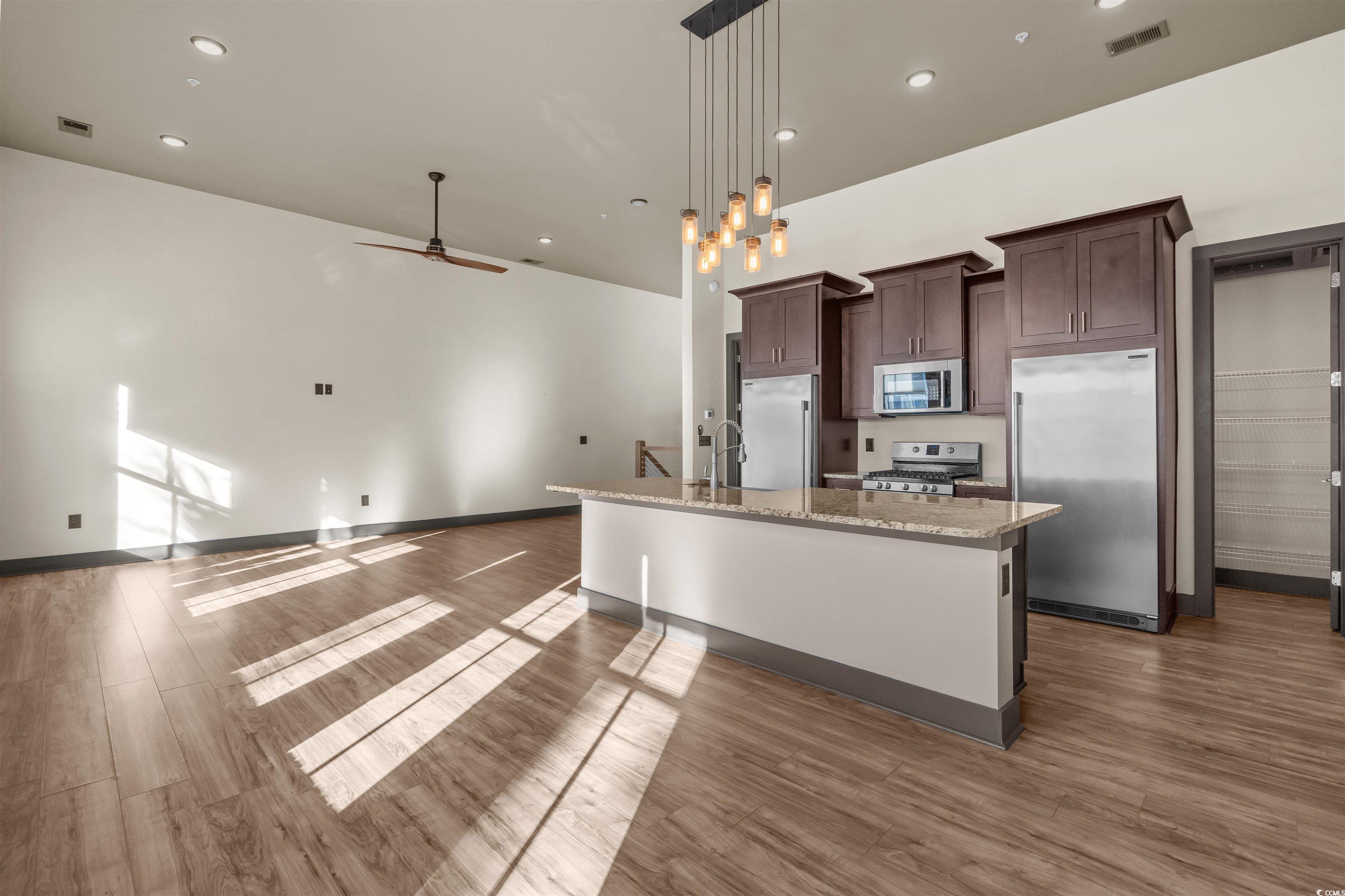80 Shady Oak Lane Murrells Inlet, SC 29576 - Photo 31 of 31 Kitchen with open floor plan, stainless steel appliances, dark brown cabinets, recessed lighting, and light stone countertops