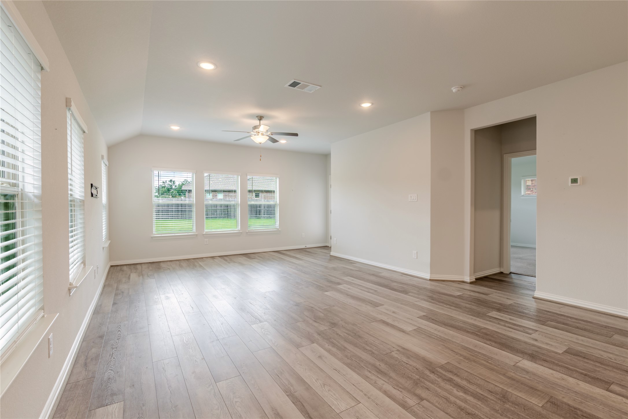 1117 Terrace View Georgetown, TX 78628 - Photo 13 of 25 Spacious living area featuring wood-finish flooring, white walls, and multiple windows with horizontal blinds