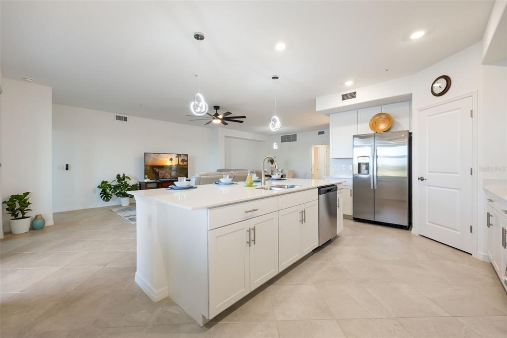 14186 Poppy Fld Loop, Unit 4911 Punta Gorda, FL 33955 - Photo 19 of 48 a large white kitchen with a refrigerator a stove a sink a dining table and chairs with wooden floor