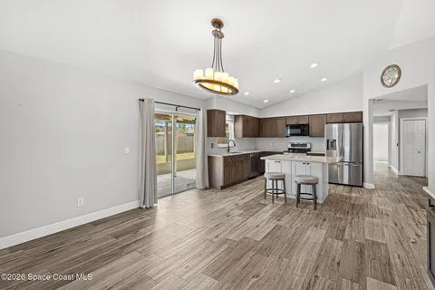 a kitchen with stainless steel appliances kitchen island granite countertop a refrigerator and a wooden floor