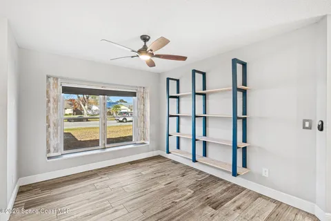 a view of an empty room with a window and wooden floor