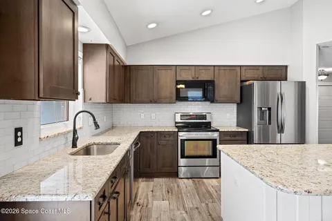 a kitchen with granite countertop a sink a stove and refrigerator