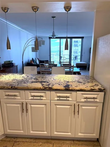 a kitchen with granite countertop a stove a sink a refrigerator dining table and chairs