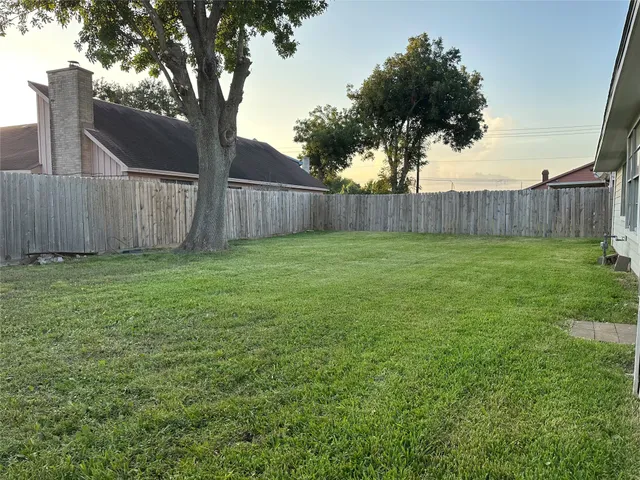 a view of a yard with wooden fence and a large tree
