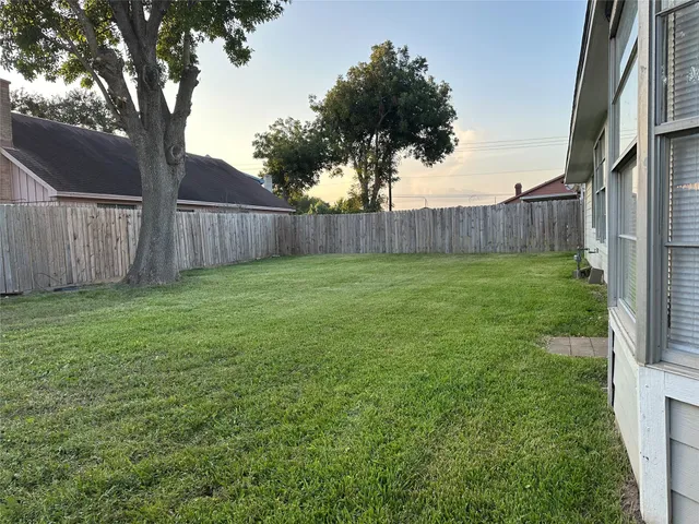 a view of a yard with an tree and wooden fence