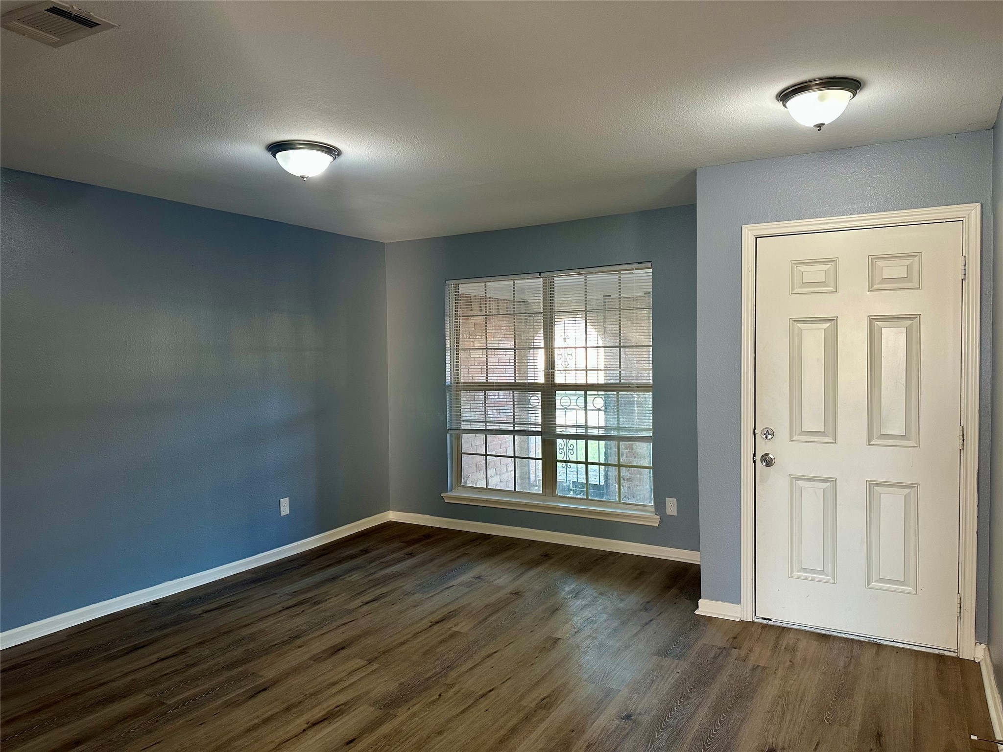 15770 Chimney Rock Road Houston, TX 77489 - Photo 6 of 42 an empty room with wooden floor and windows with curtains
