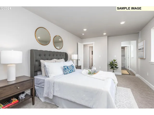 a bedroom with a bed a mirror and a lamp on dresser