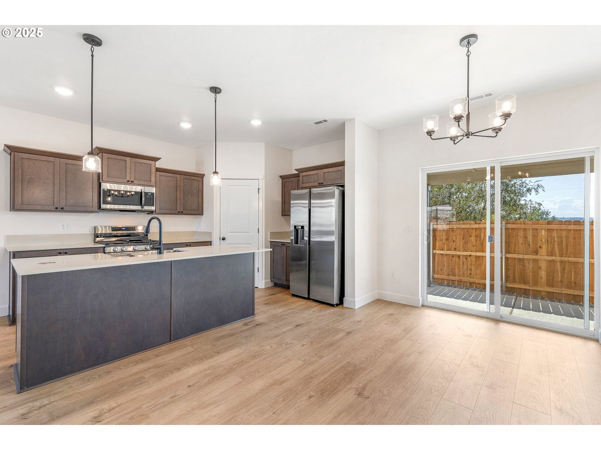 1734 Northeast 9th Street Hermiston, OR 97838 - Photo 26 of 31 a kitchen with stainless steel appliances kitchen island granite countertop a refrigerator a stove a sink and a wooden floor