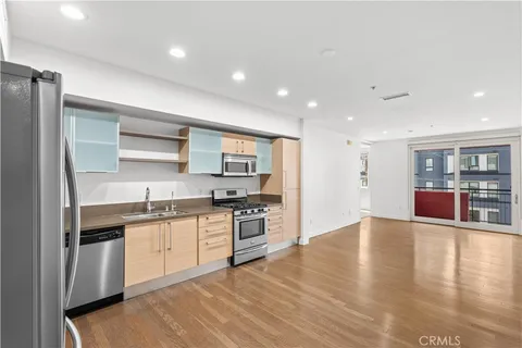 a kitchen with stainless steel appliances granite countertop a stove top oven a sink dishwasher and a refrigerator with wooden floor