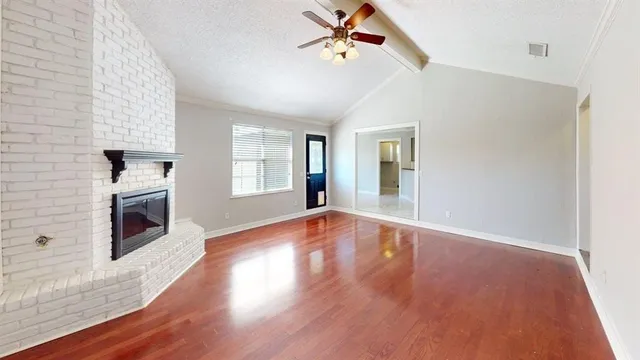 a view of empty room with fireplace and wooden floor