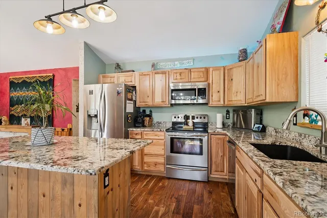 a kitchen with stainless steel appliances granite countertop a sink stove refrigerator and cabinets