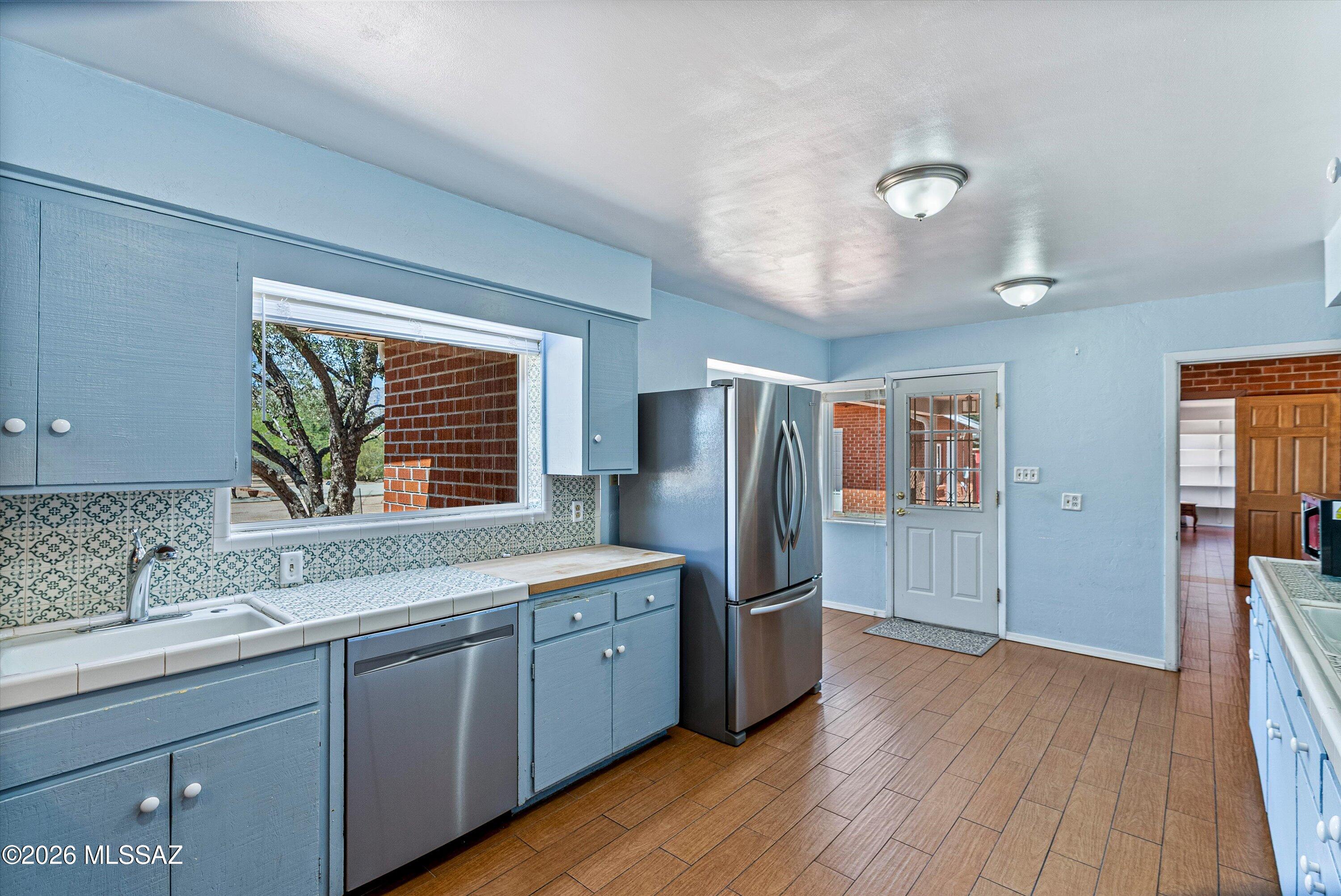 2107 East Lind Road Tucson, AZ 85719 - Photo 16 of 43 a kitchen with stainless steel appliances granite countertop a refrigerator a sink dishwasher and wooden cabinets with wooden floor