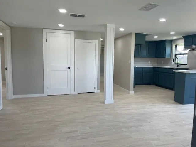 a view of an empty room with kitchen and window