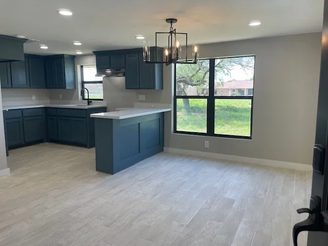 a kitchen with kitchen island granite countertop a stove top oven a sink and a granite counter top