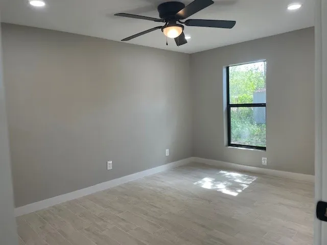 an empty room with a window and ceiling fan